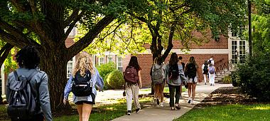 Students walking with backpacks on to a building.